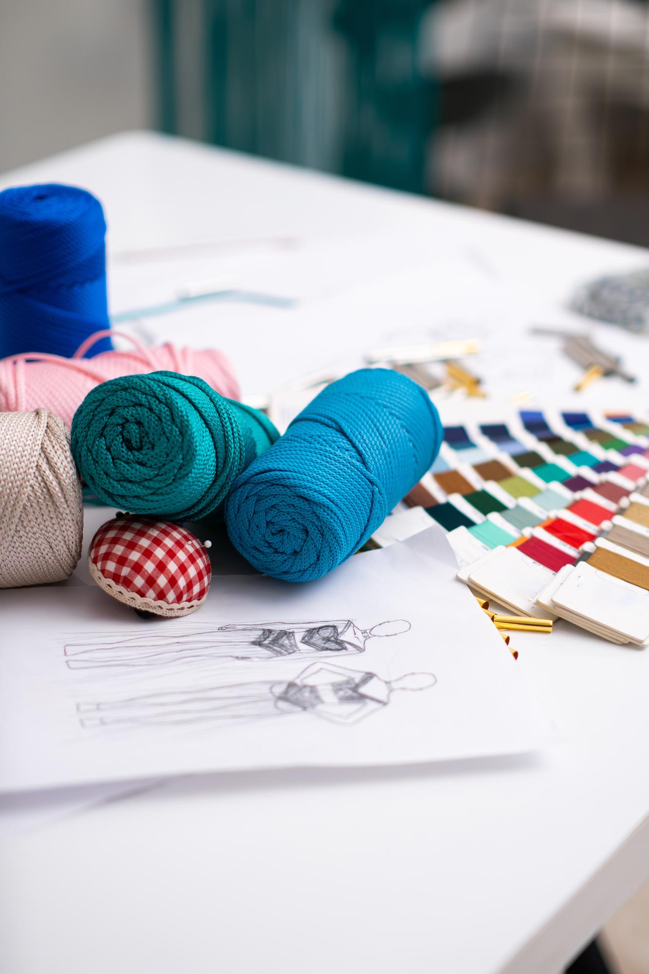 Assortment of thread spools and pattern sketches on table